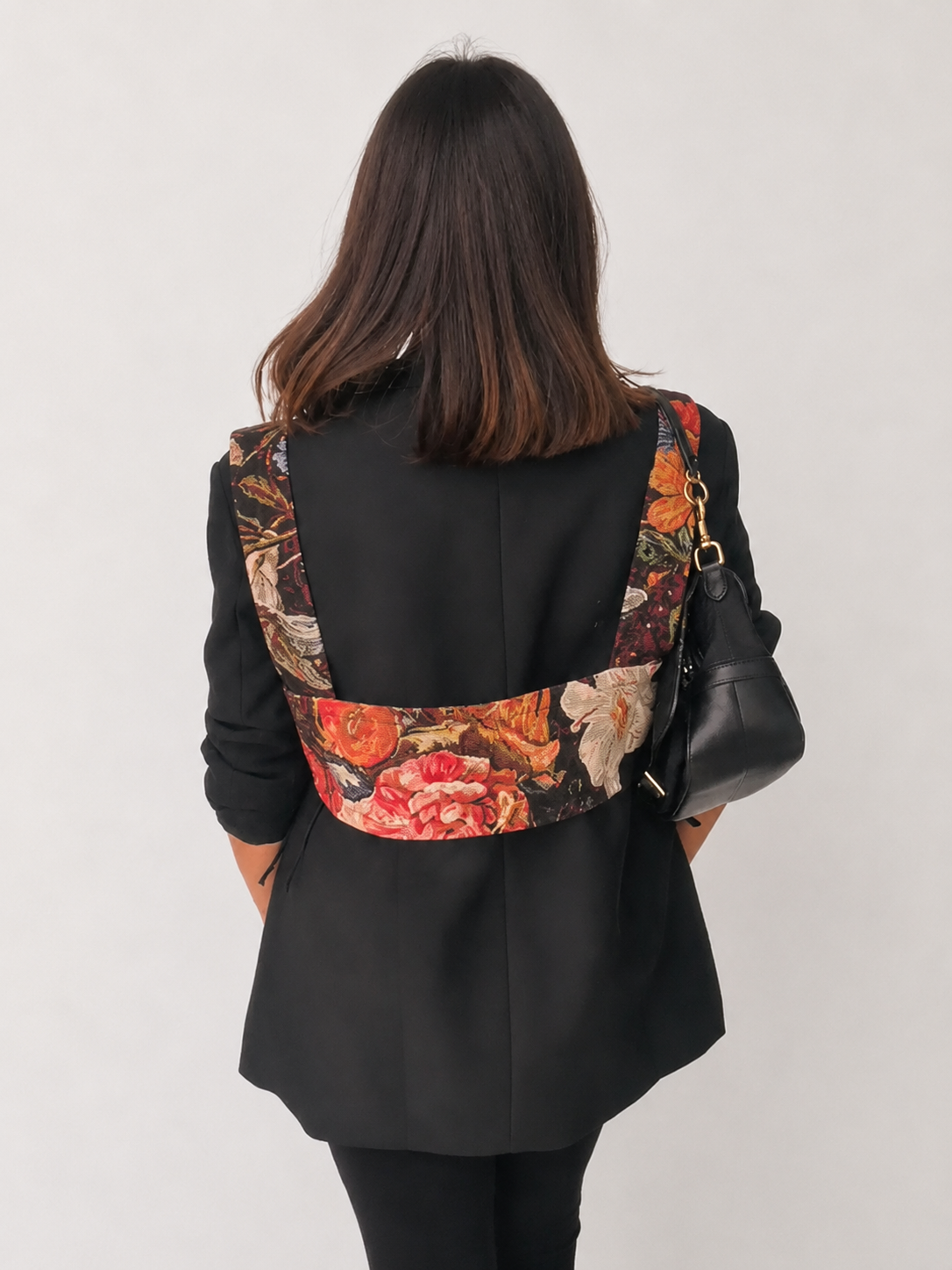 Back view of multicolour woven harness bib layered over a black blazer.