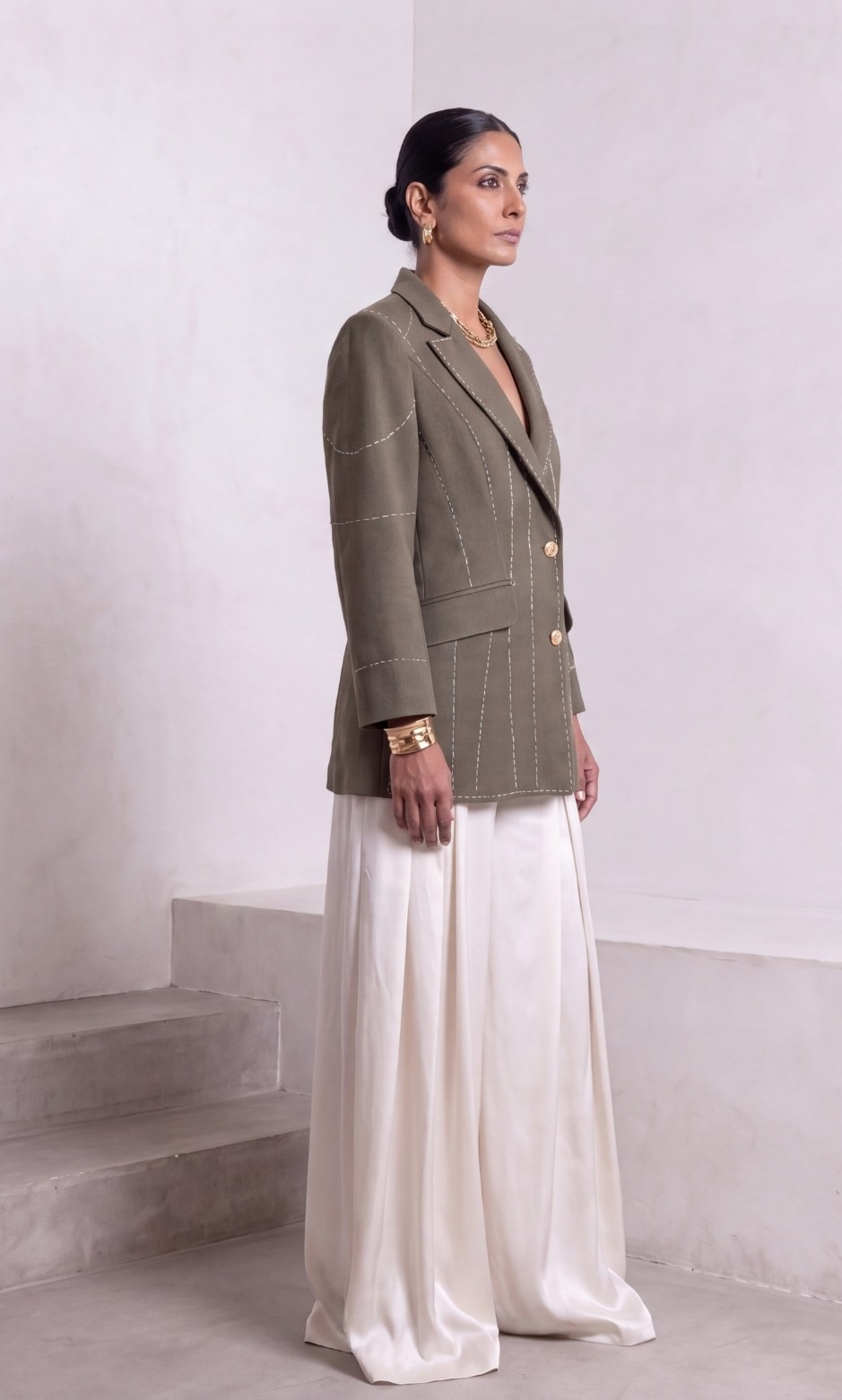 Dark olive green Debrief blazer with contrast white stitch detailing styled with ivory wide-leg trousers.