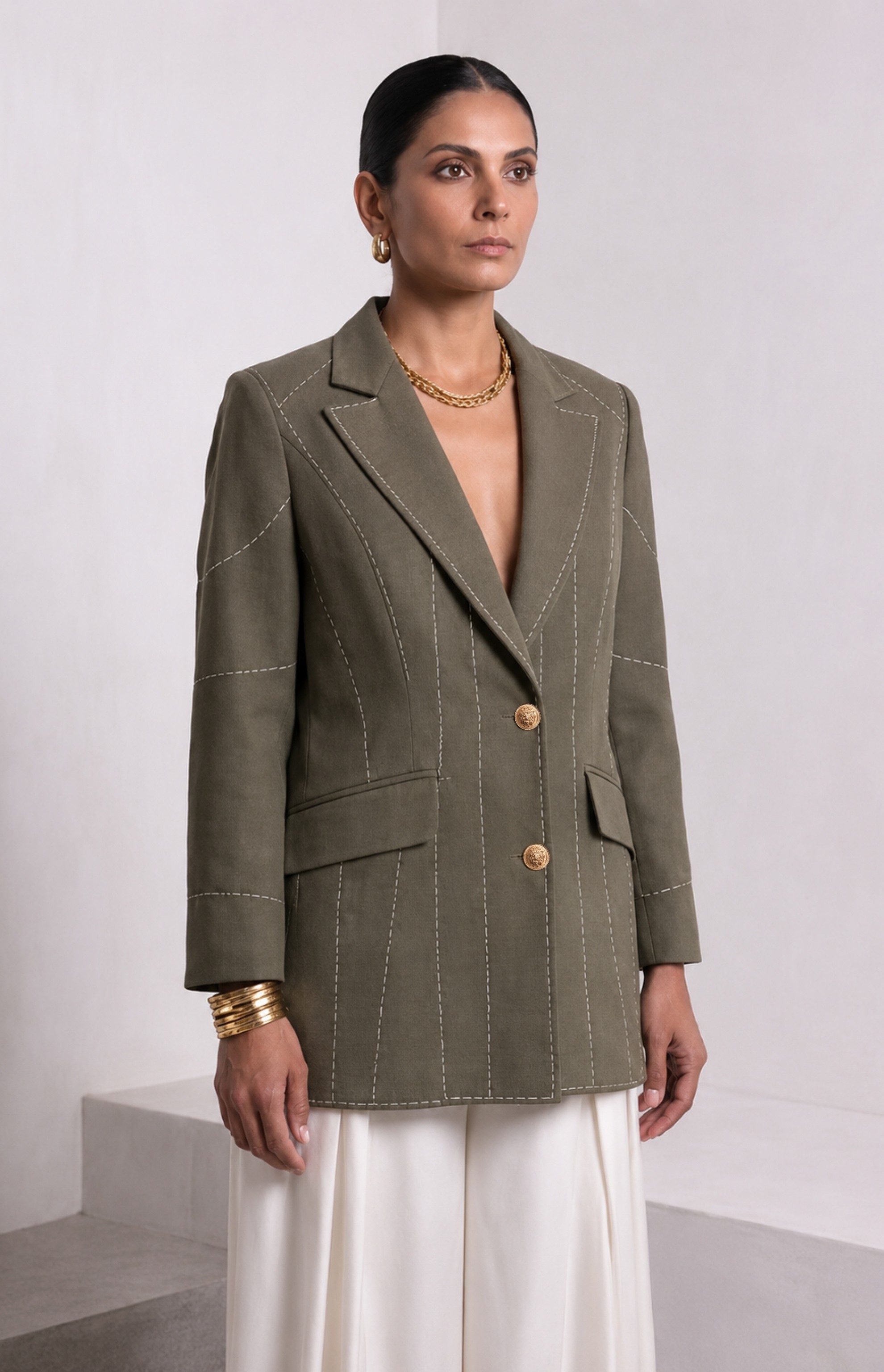 Front view of dark olive green Debrief blazer with contrast white stitching and gold buttons.