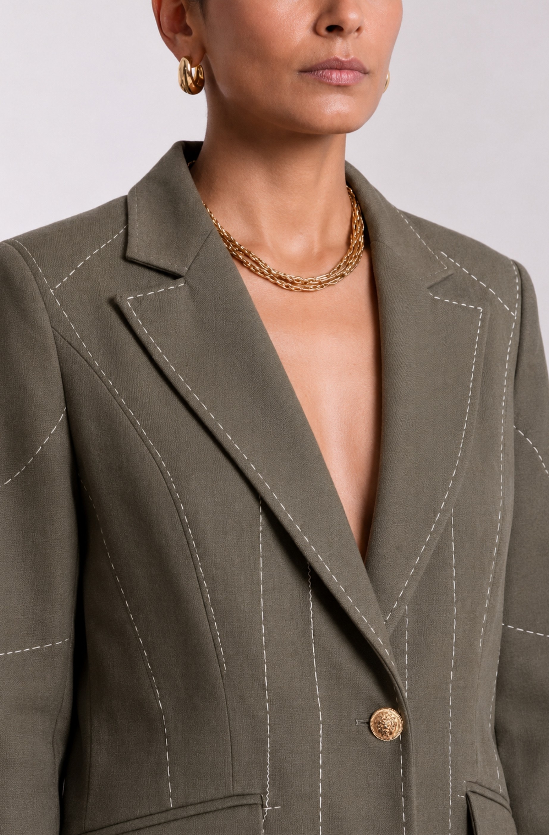 Close-up of dark olive green Debrief blazer lapels and contrast white stitch detailing.