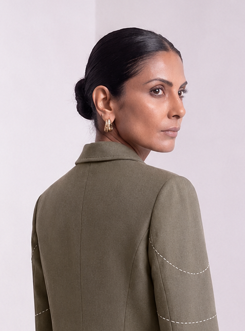 Close-up back and shoulder view of dark olive green Debrief blazer with contrast stitching.