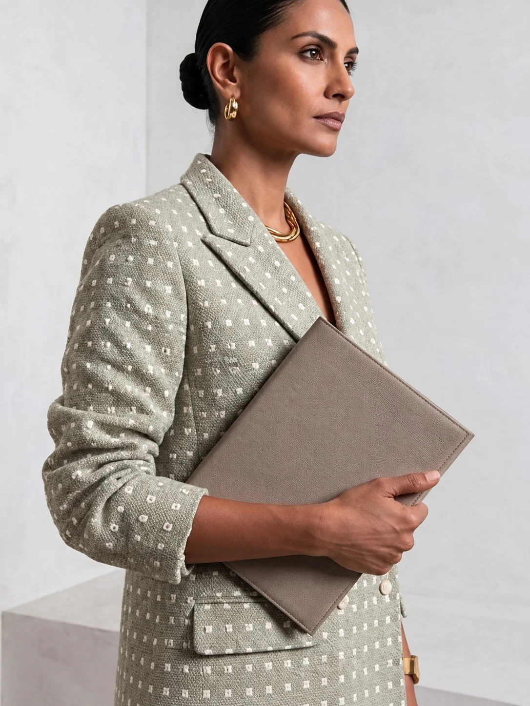 Side view of light sage green Ping Me blazer styled with a neutral clutch.