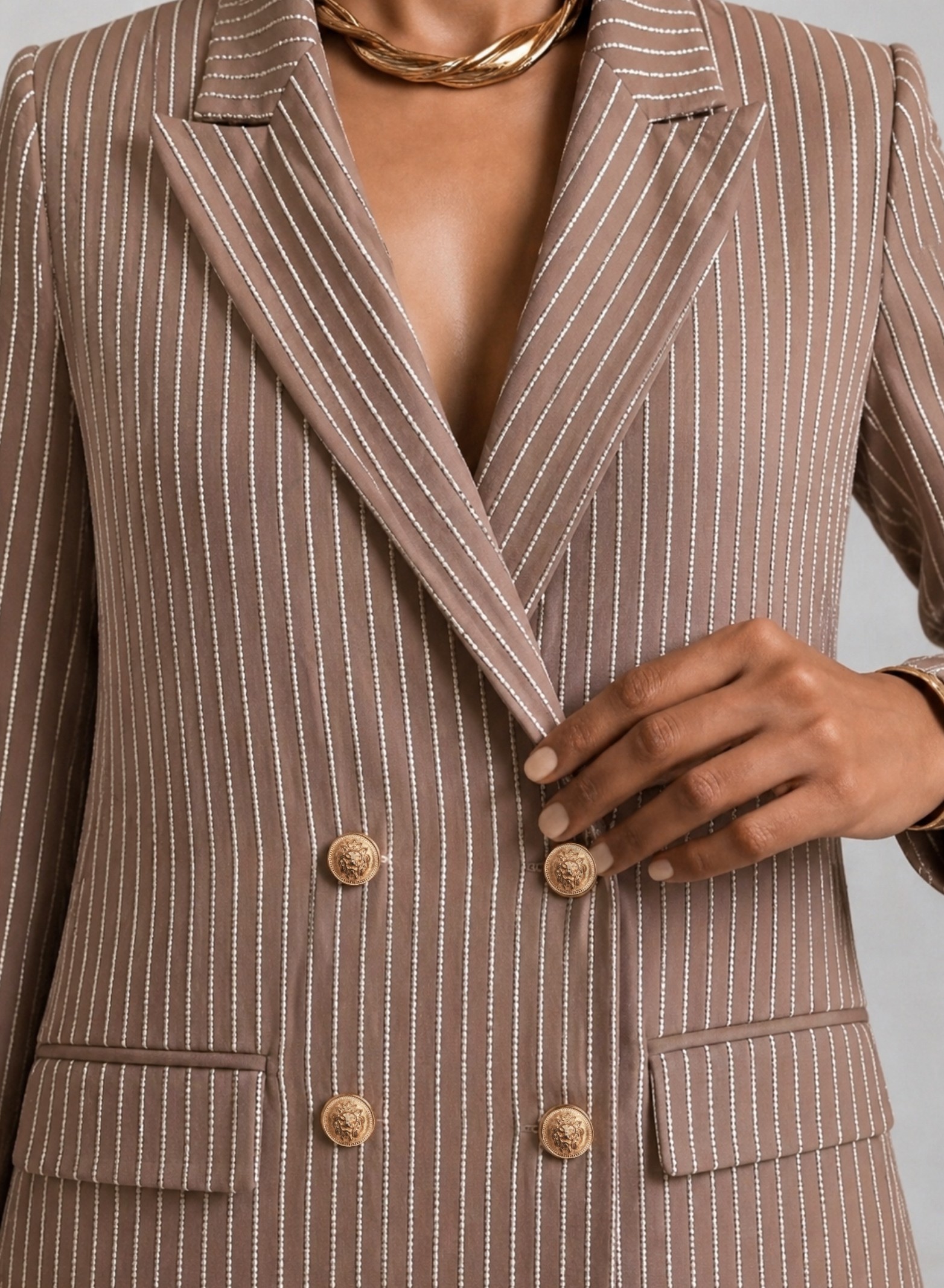 Close-up of taupe EOD blazer showing pearl-beaded stripes, notch lapels and gold lion-head buttons.