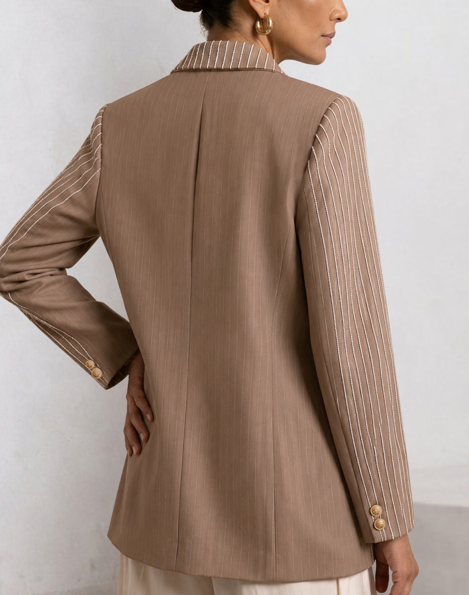 Back angled view of taupe EOD blazer showing striped sleeves, collar and clean back panel.