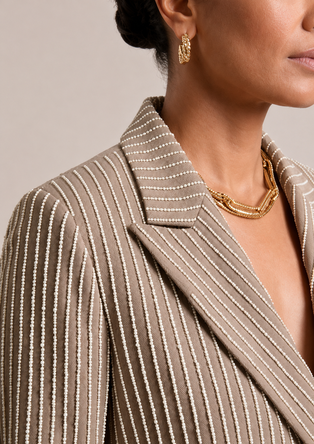 Close-up of taupe EOD blazer shoulder and lapel with pearl-beaded stripe detailing.
