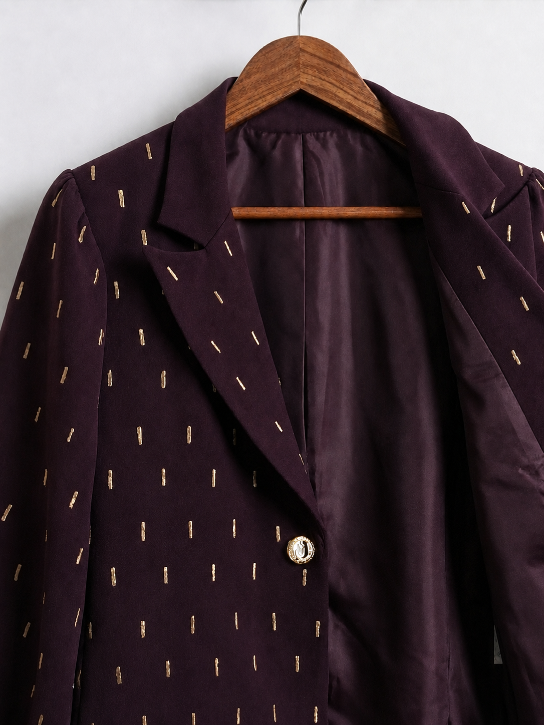 Front detail of plum blazer showing gold embroidery, lapel, lining and gold-tone button.