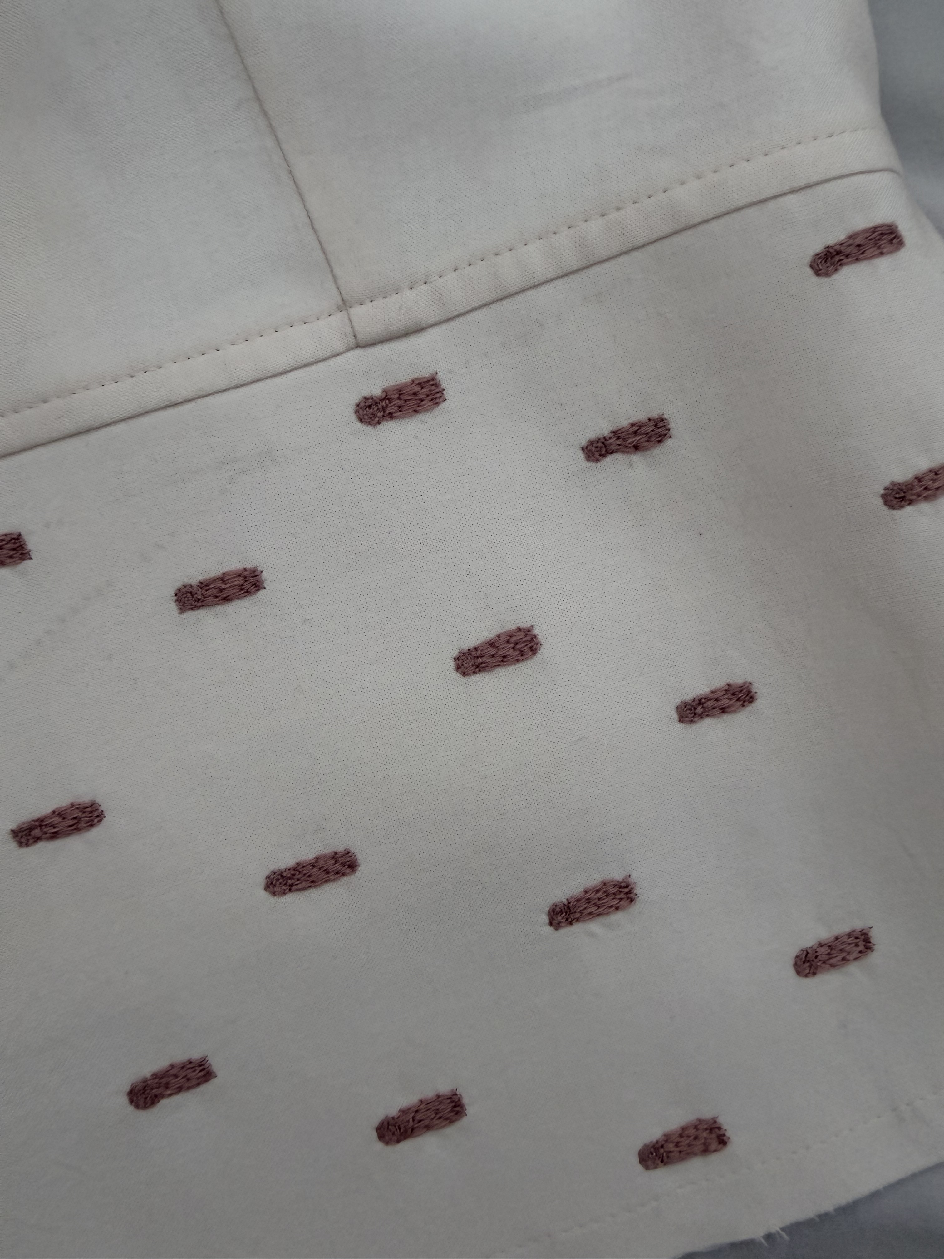 Close-up of mauve raised stitch motifs on cream WIP tailored vest.