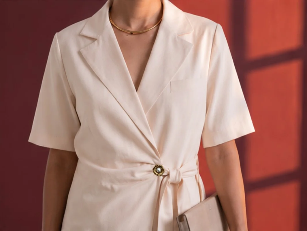 Close-up front view of cream Final Draft blazer showing notch lapels, self-tie waist and pearl-centered statement button.
